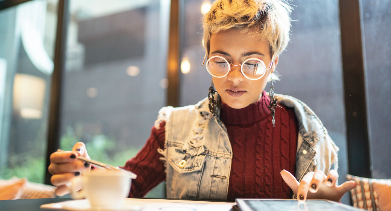 A woman sits on a table and looks at her bank statement, indicating she wants to develop better money habits. 